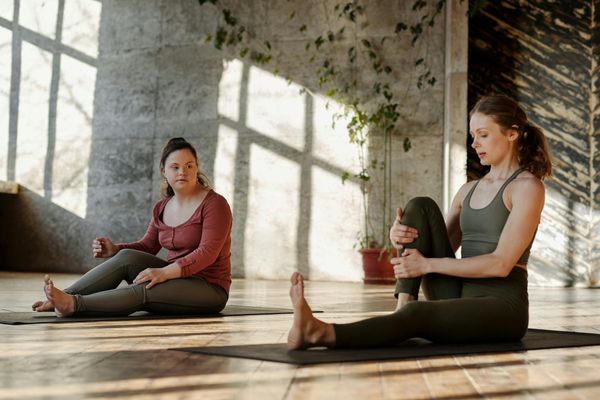 A person in athletic wear stretching on a yoga mat in a sunlit room.